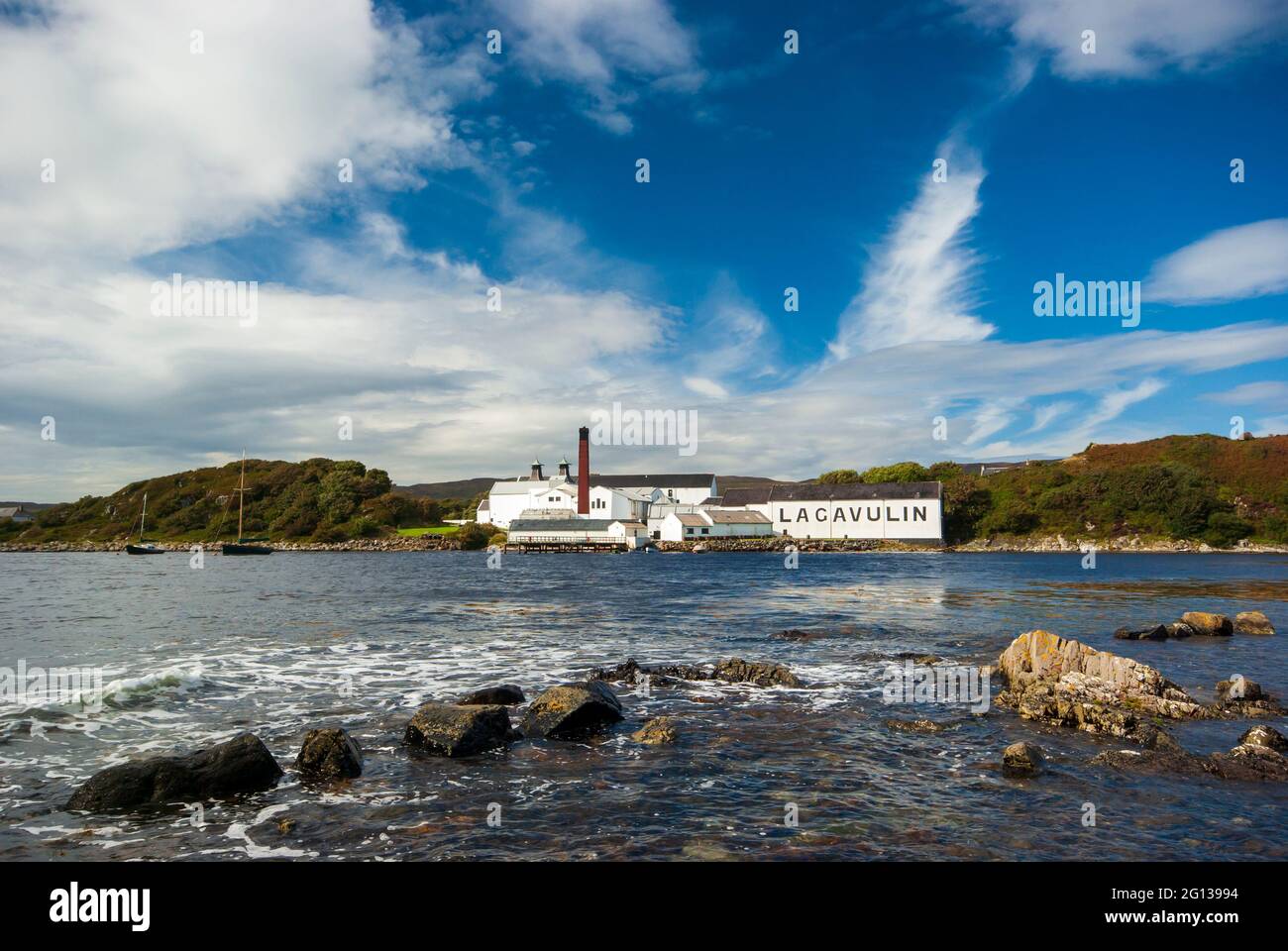 Una vista attraverso la piccola baia agli edifici della distilleria di whisky Lagavulin sull'Isola di Islay in Scozia. Foto Stock
