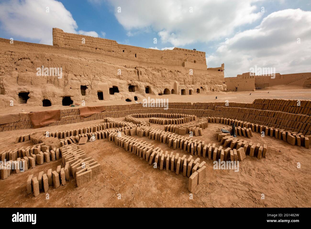 Brickyard con lo storico castello di Naryn sullo sfondo della città vecchia di Meybod, Iran Foto Stock