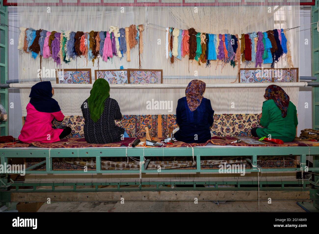 Donne iraniane tessono tappeti persiani nel laboratorio di tappeti a Naein, Iran. Foto Stock