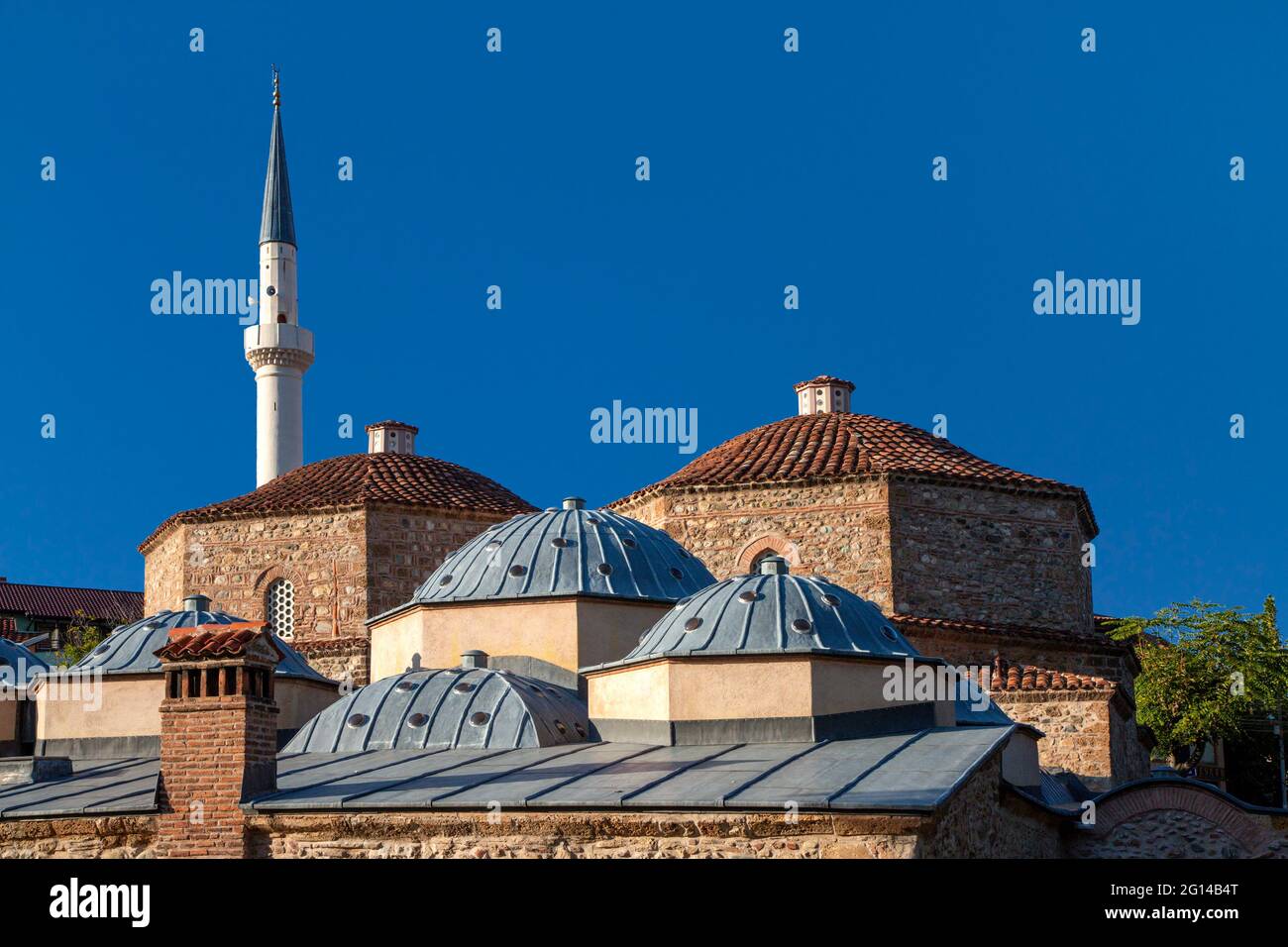 Cupole dello storico bagno turco con un minareto sullo sfondo, a Prizren, Kosovo Foto Stock