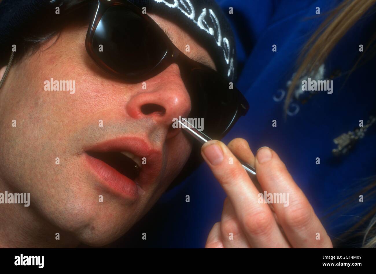 uomo che ha i suoi capelli nasali strappati dal naso con delle pinzette Foto Stock