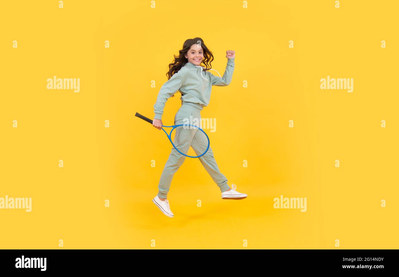 felice energica ragazza teen salto in abbigliamento sportivo con badminton racchetta in esecuzione al successo, sbrigati. Foto Stock