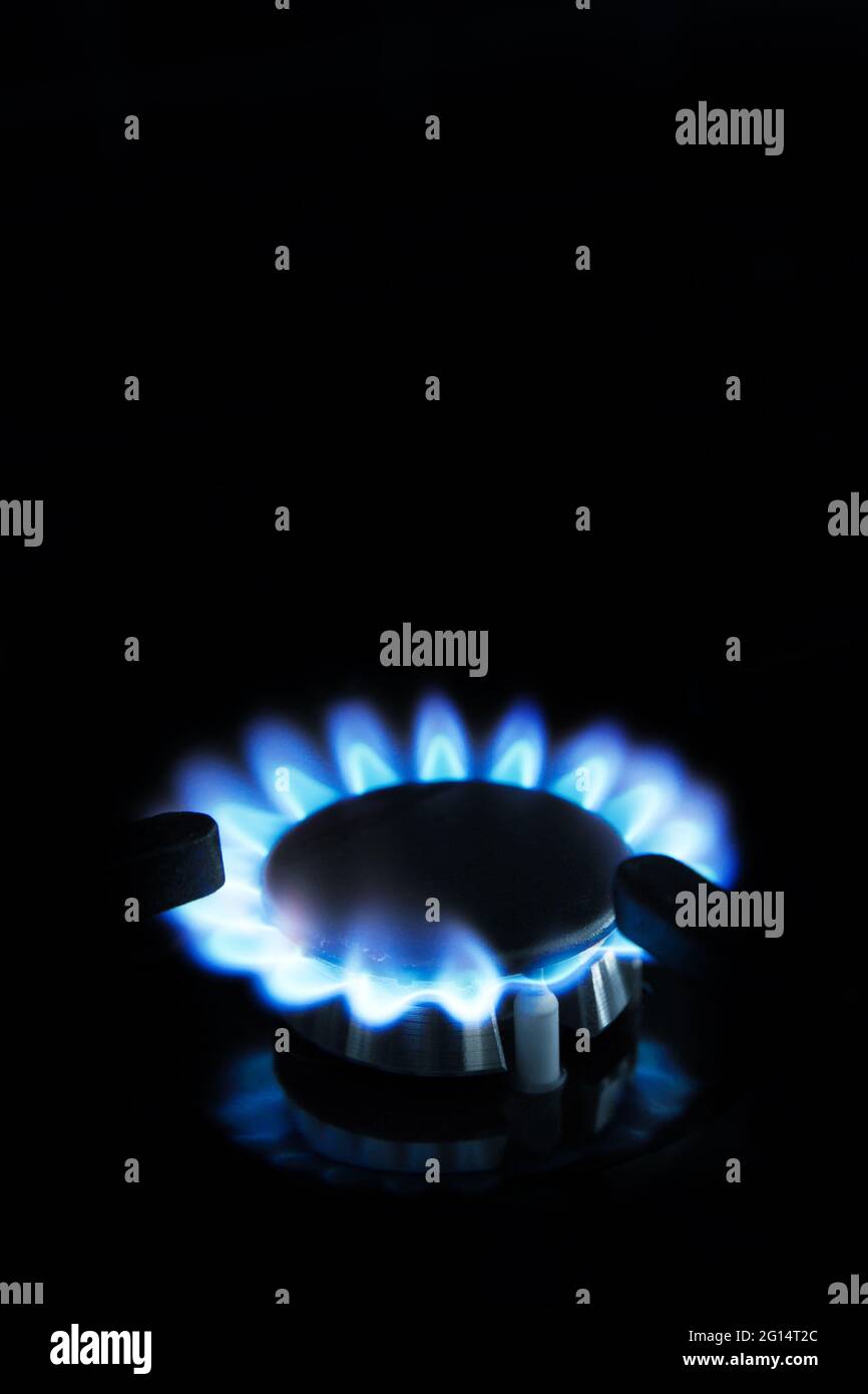 Un primo piano della fiamma blu del gas naturale su un fornello o piano cottura Foto Stock