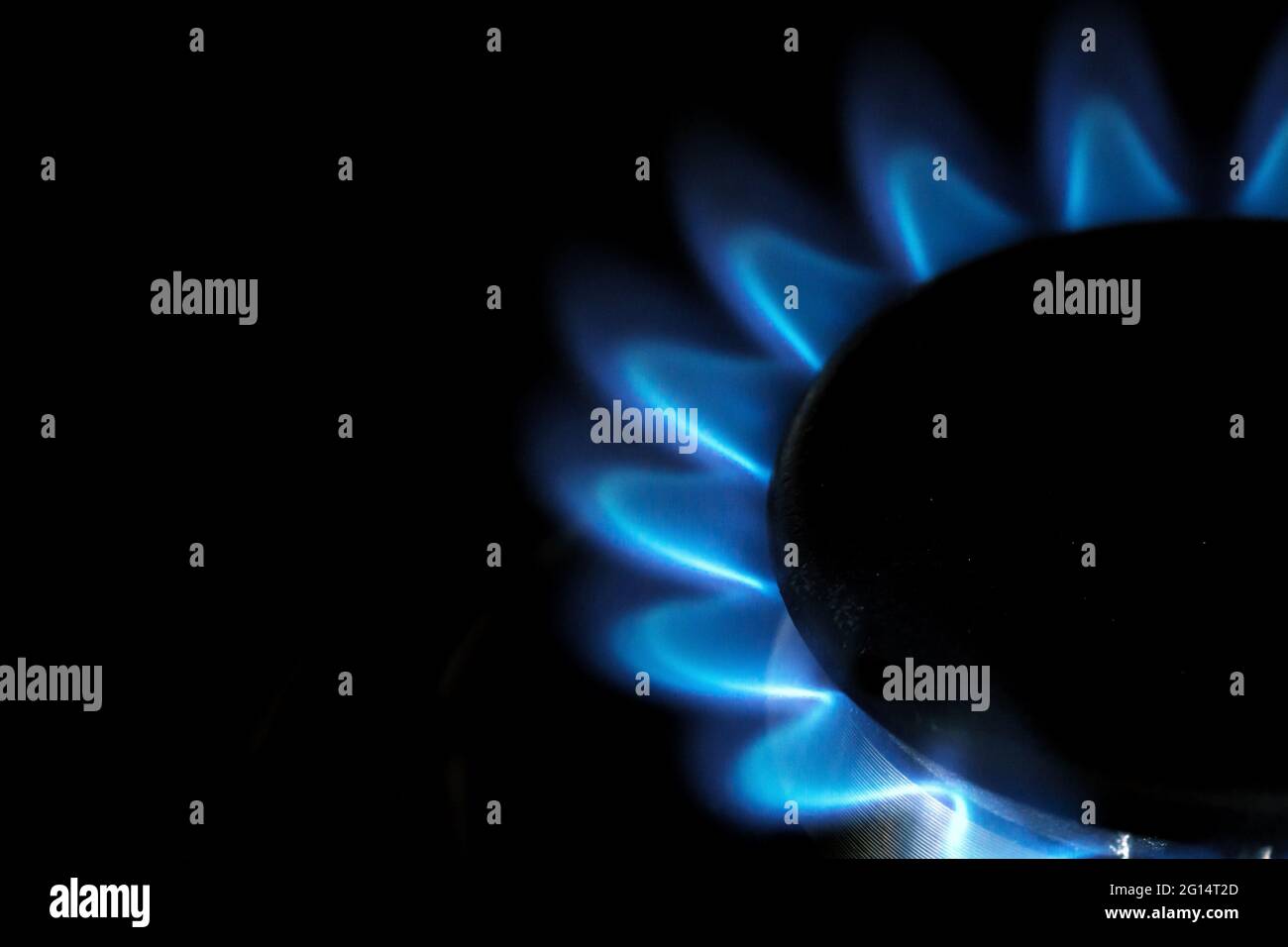 Un primo piano della fiamma blu del gas naturale su un fornello o piano cottura Foto Stock