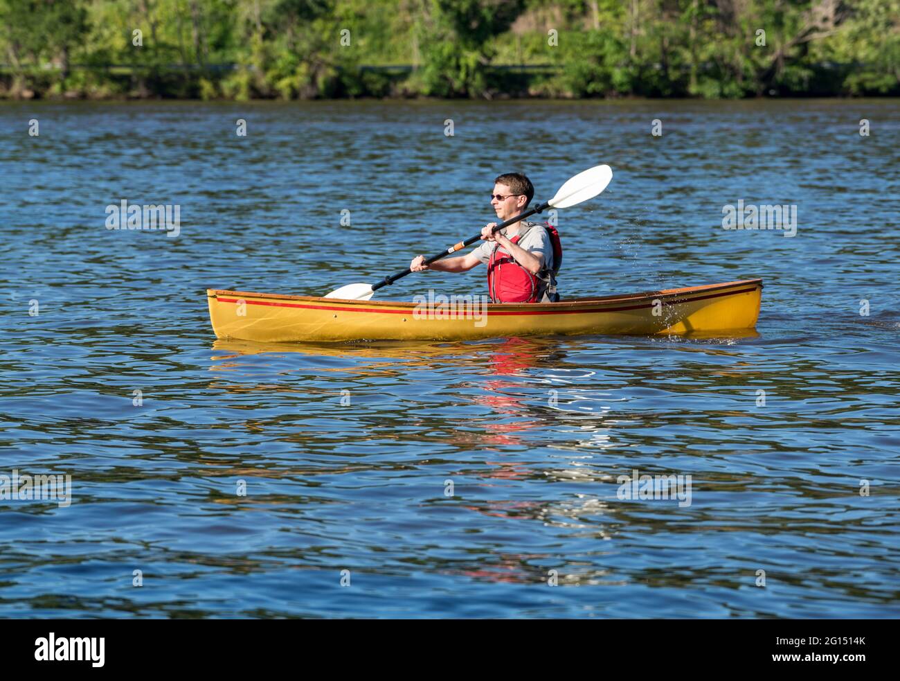 Giovane uomo in giubbotto di salvataggio che va in canoa con un kayak su un lago nella Virginia occidentale Foto Stock