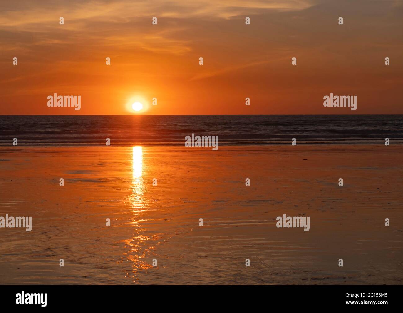 Tramonto su Cable Beach a Broome Australia Occidentale con cielo arancione, sole e spiaggia di sabbia bagnata. Foto Stock