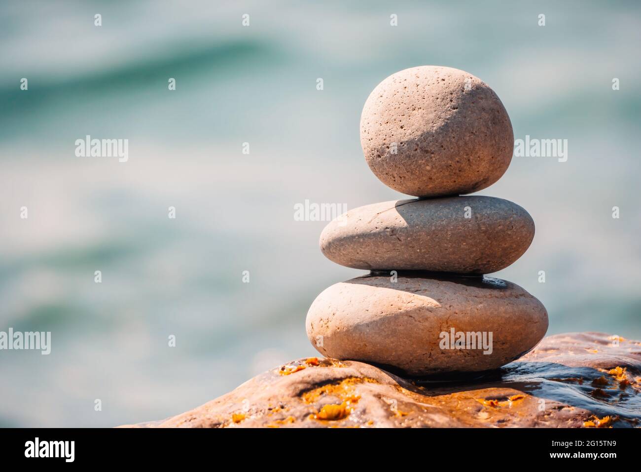 Equilibrata piramide di ciottoli sulla spiaggia in una giornata di sole. Abstract Sea bokeh sullo sfondo. Messa a fuoco selettiva. Pietre Zen sulla spiaggia di mare, meditazione Foto Stock