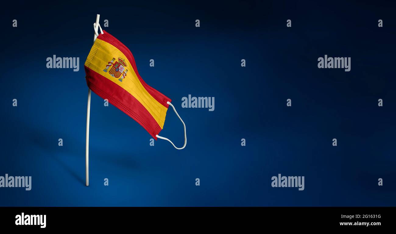 Bandiera ondulata della Spagna dipinta su maschera medica sul palo. Concetto del banner della lotta contro l'epidemia coronavirus COVID-19. Spazio di copia Foto Stock