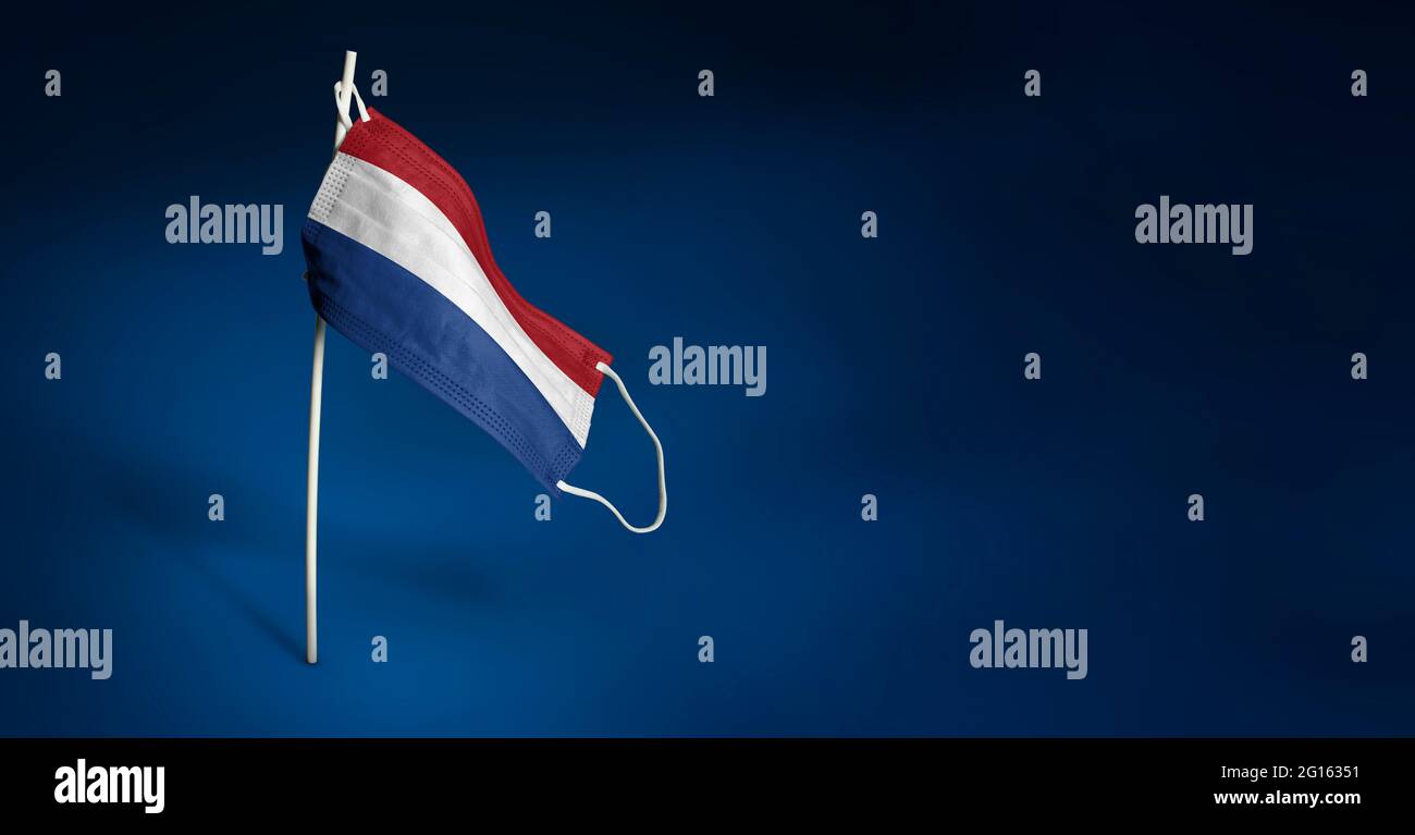 Bandiera ondulata dei Paesi Bassi dipinta su maschera medica sul palo. Concetto del banner della lotta contro l'epidemia coronavirus COVID-19. Copia spa Foto Stock