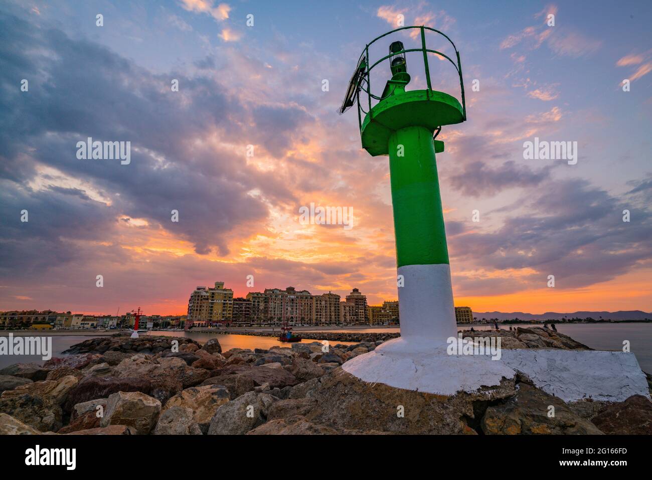 Vista del faro all'ingresso della baia di Port Sauslaya durante un tramonto colorato. Valencia Foto Stock
