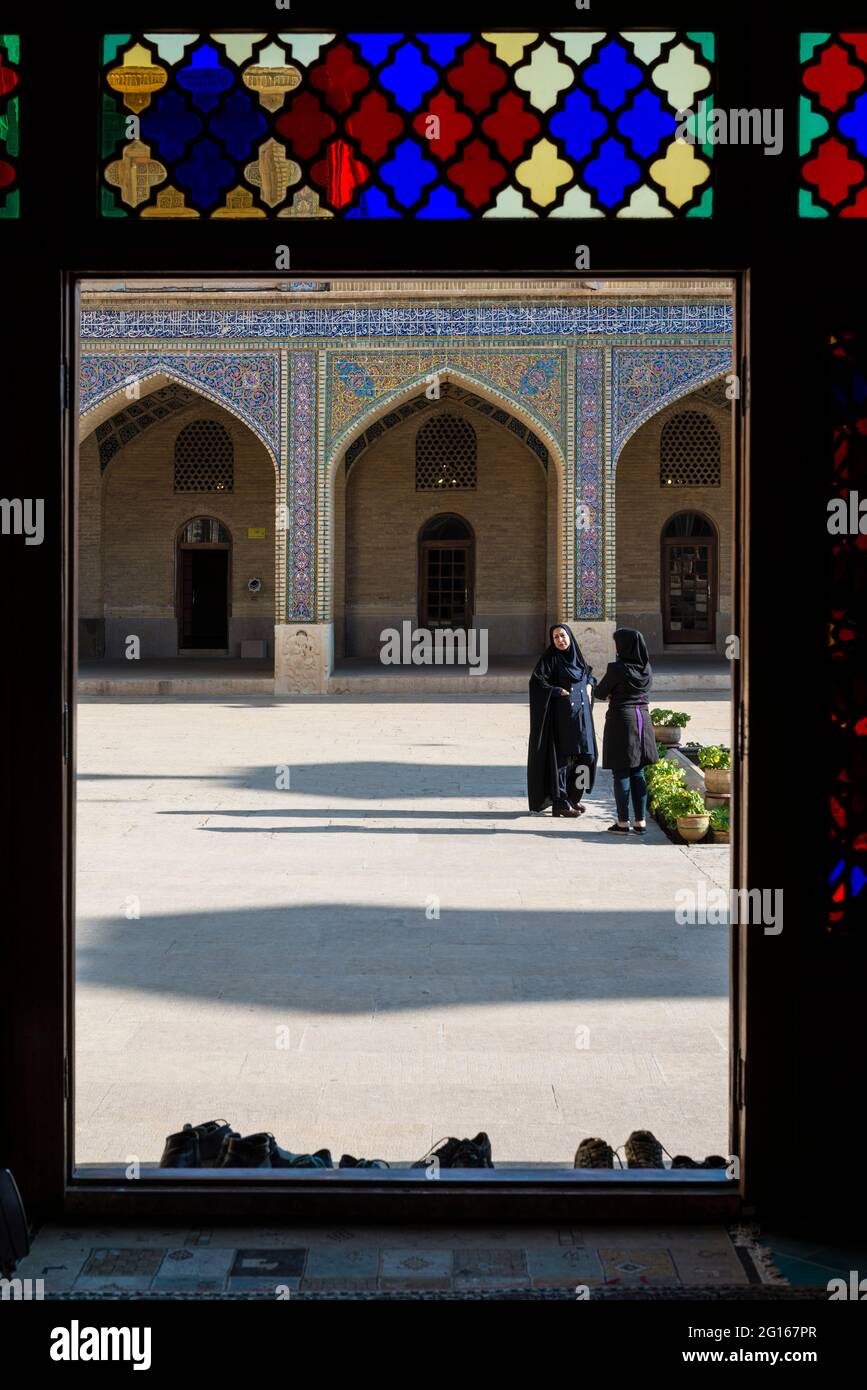 Due donne nel cortile della moschea Nasir-ol-Molk (Moschea Rosa) visto dalla sala di preghiera invernale in vetro colorato. Shiraz, Provincia di Fars, Iran Foto Stock