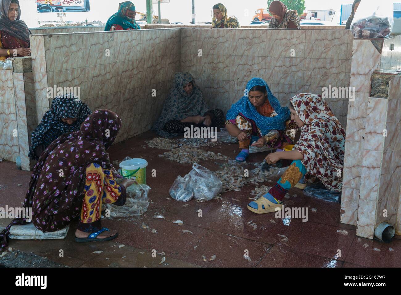 Mercato del pesce a Bandar Abbas, provincia di Hormozgān, Iran. Donne Bandari che si staccano i gamberi sul pavimento. Foto Stock