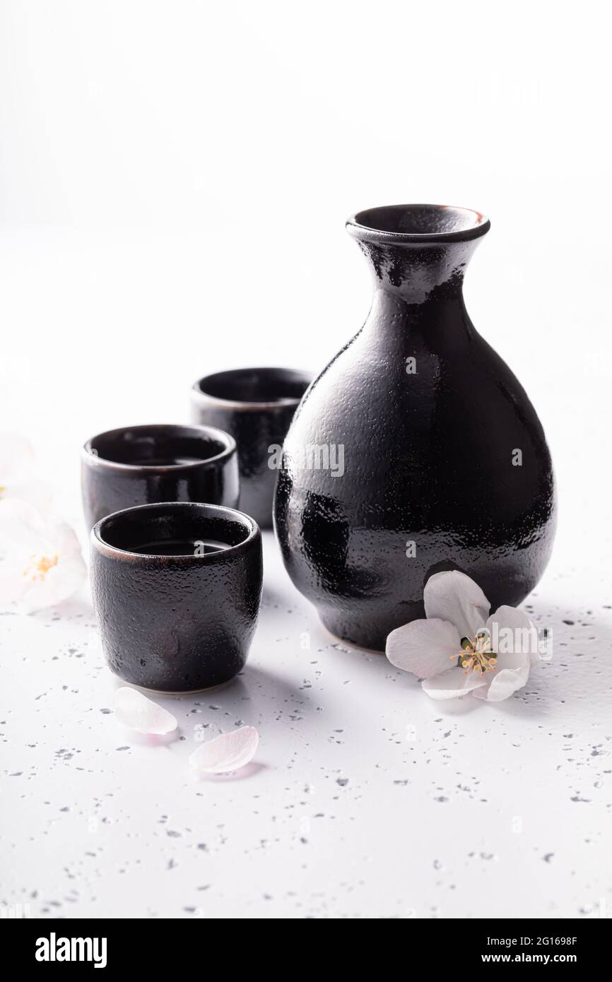 Sake giapponese come alcol tradizionale. Sake tradizionalmente servito in  ceramica. Ceramica nera su una pietra bianca Foto stock - Alamy