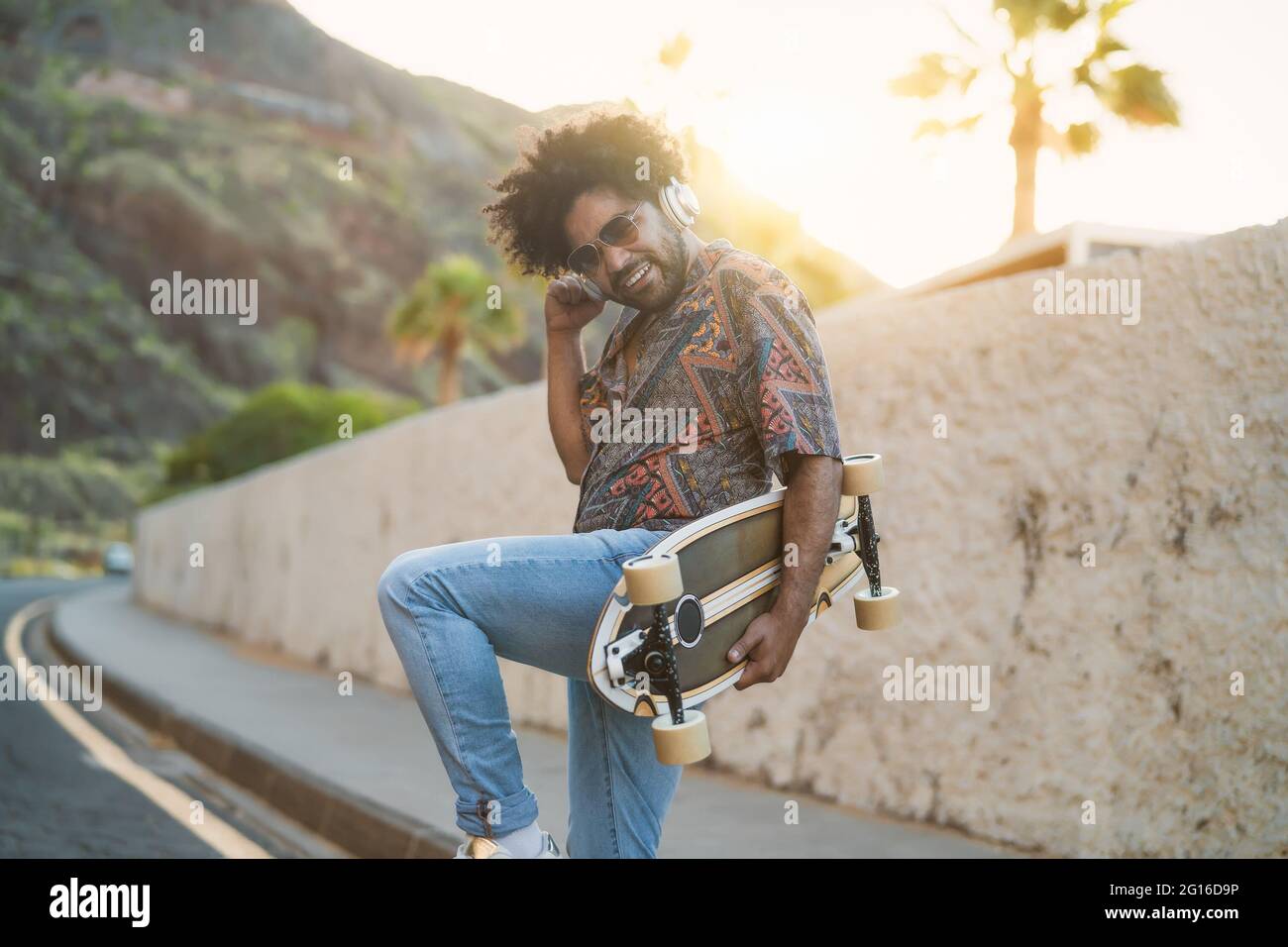 Felice uomo afro divertirsi ballando e ascoltando musica con le cuffie wireless durante l'estate - concetto di stile di vita dei giovani Foto Stock