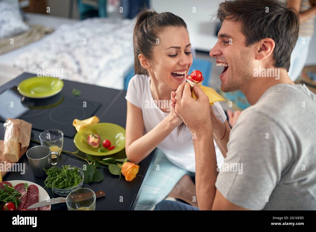 Una giovane coppia ama nutrirsi mentre si serve la colazione in un'atmosfera allegra a casa. Amore, insieme, colazione, casa Foto Stock