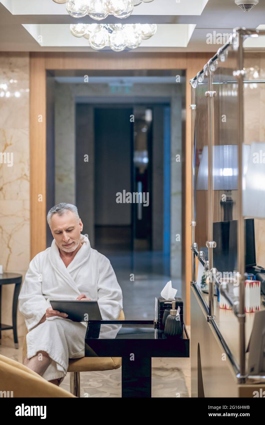 Un uomo in un accappatoio bianco seduto in un centro termale Foto Stock