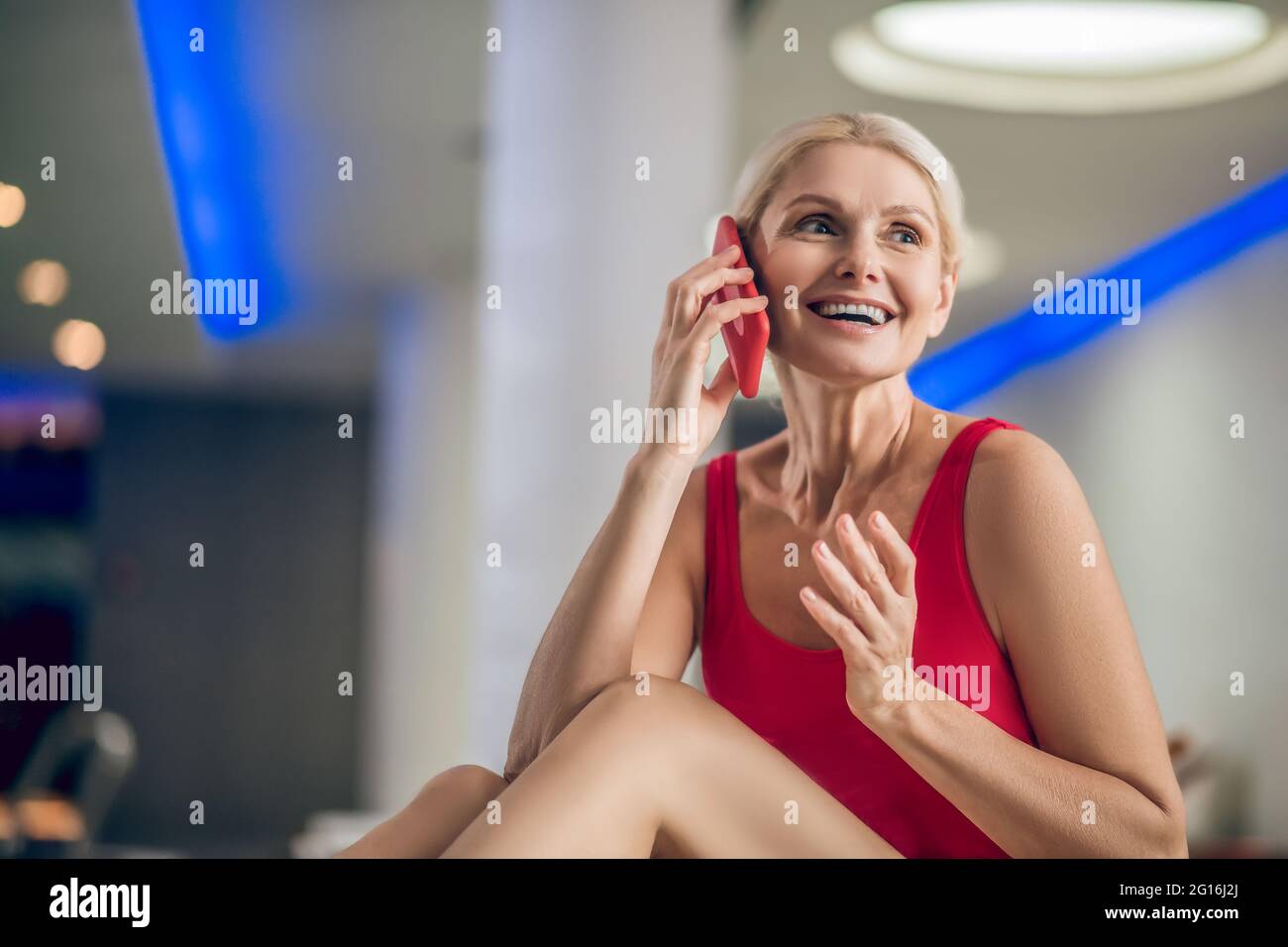 Bella donna bionda in un costume da bagno rosso con uno smartphone Foto Stock