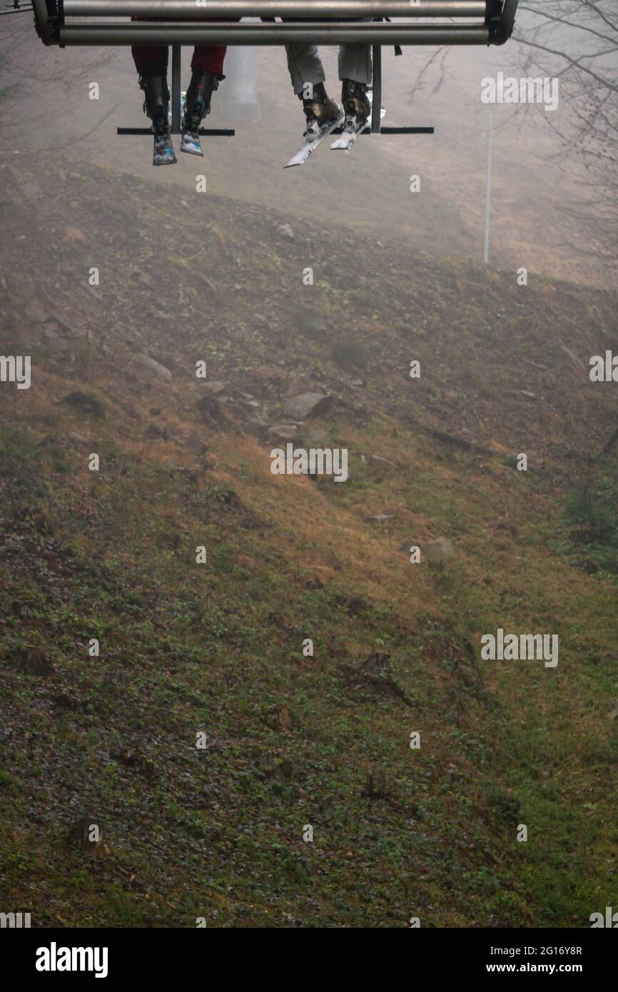 Il fuoco selettivo delle gambe dello sciatore nello skilift al Foggy Day Foto Stock