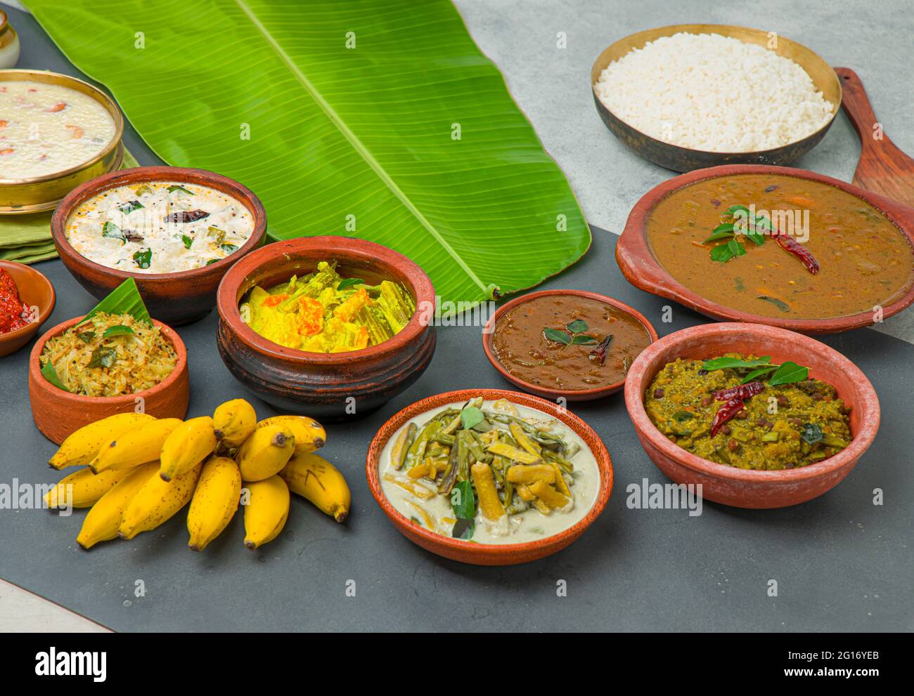 Kerala tradizionale banchetto contorni piatti e riso cotto disposti in uno sfondo a due colori con foglie di banana verde fresco posto vicino ad esso. Foto Stock