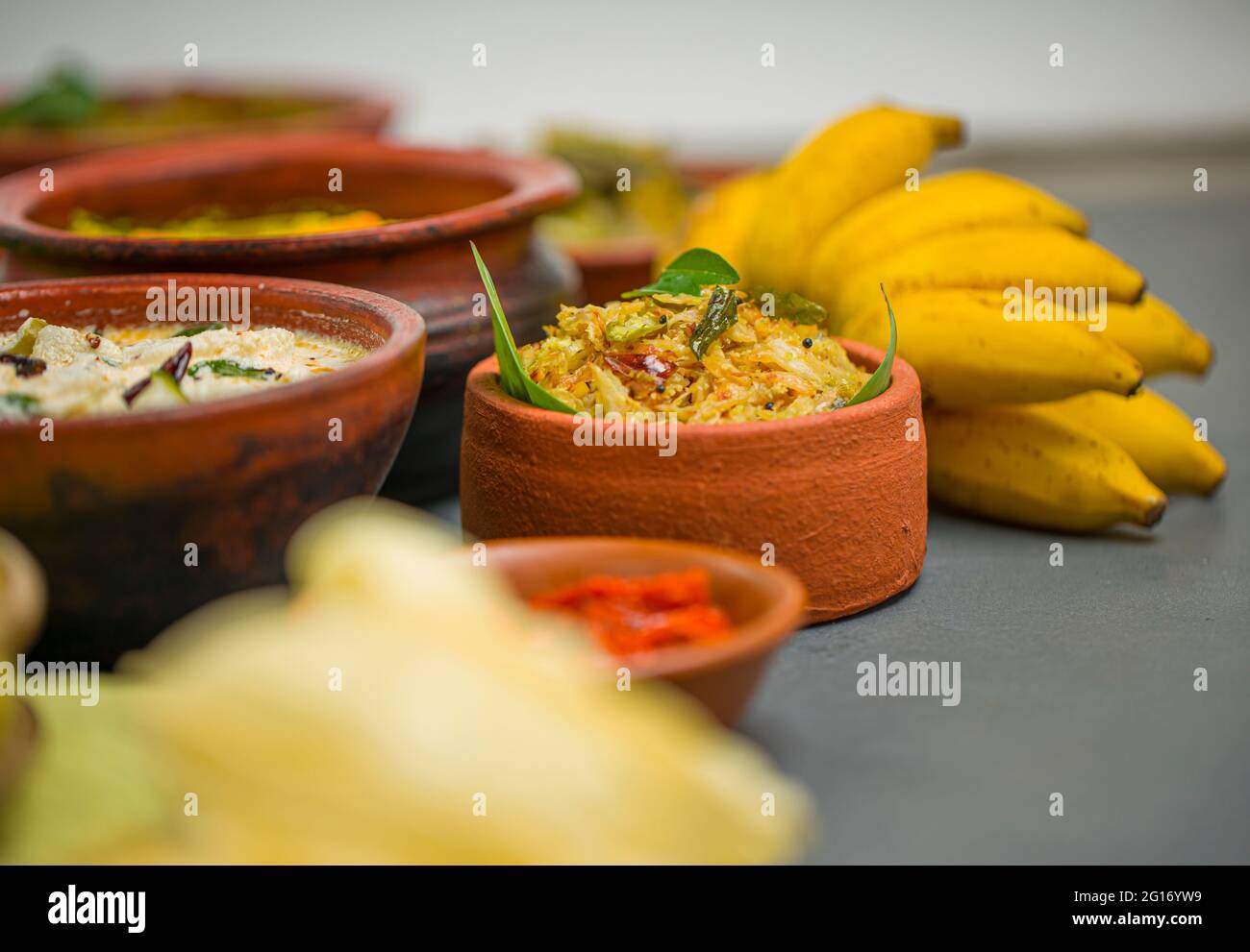 Kerala tradizionale banchetto contorni disposti su sfondo grigio, fuoco selettivo. Foto Stock