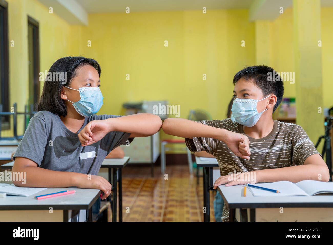Bambini asiatici con maschera di protezione di ritorno a scuola dopo covid-19 quarantena e blocco, saluto. Foto Stock