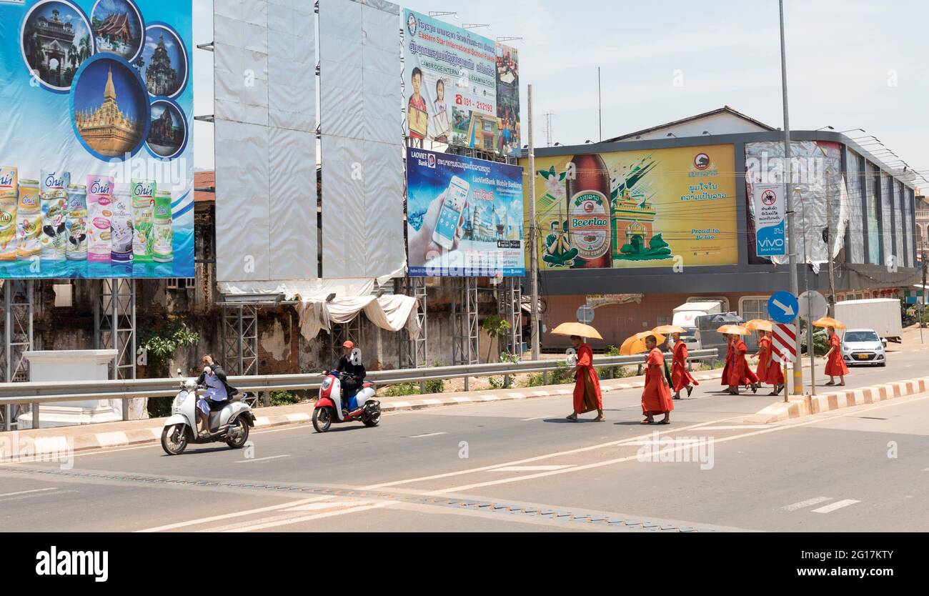 Monaci che attraversano la strada utilizzando ombrelloni come ombrelloni, Pakse, Laos Foto Stock