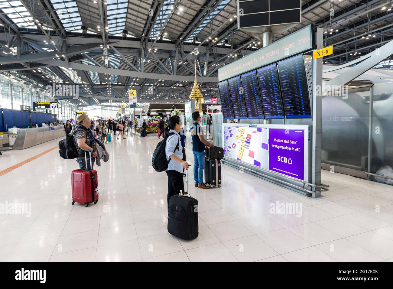 I viaggiatori che osservano le partenze salpano all'Aeroporto Suvarnabhumi, Bangkok, Thailandia Foto Stock