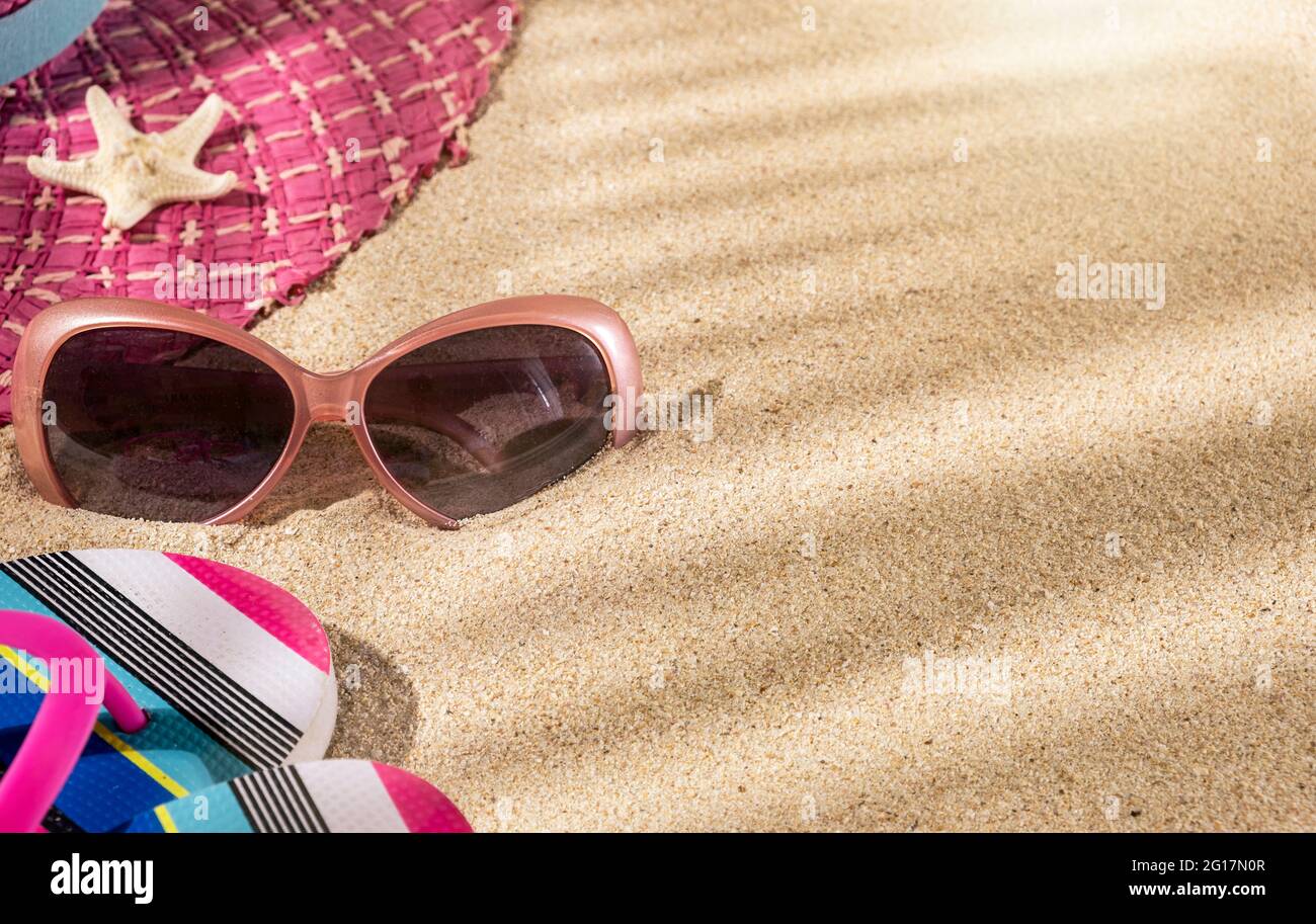 Grande cappello rosa estivo rotondo, con occhiali da sole e infradito e stella di pesce sulla spiaggia di sabbia, vista dall'alto, spazio per fotocopie Foto Stock