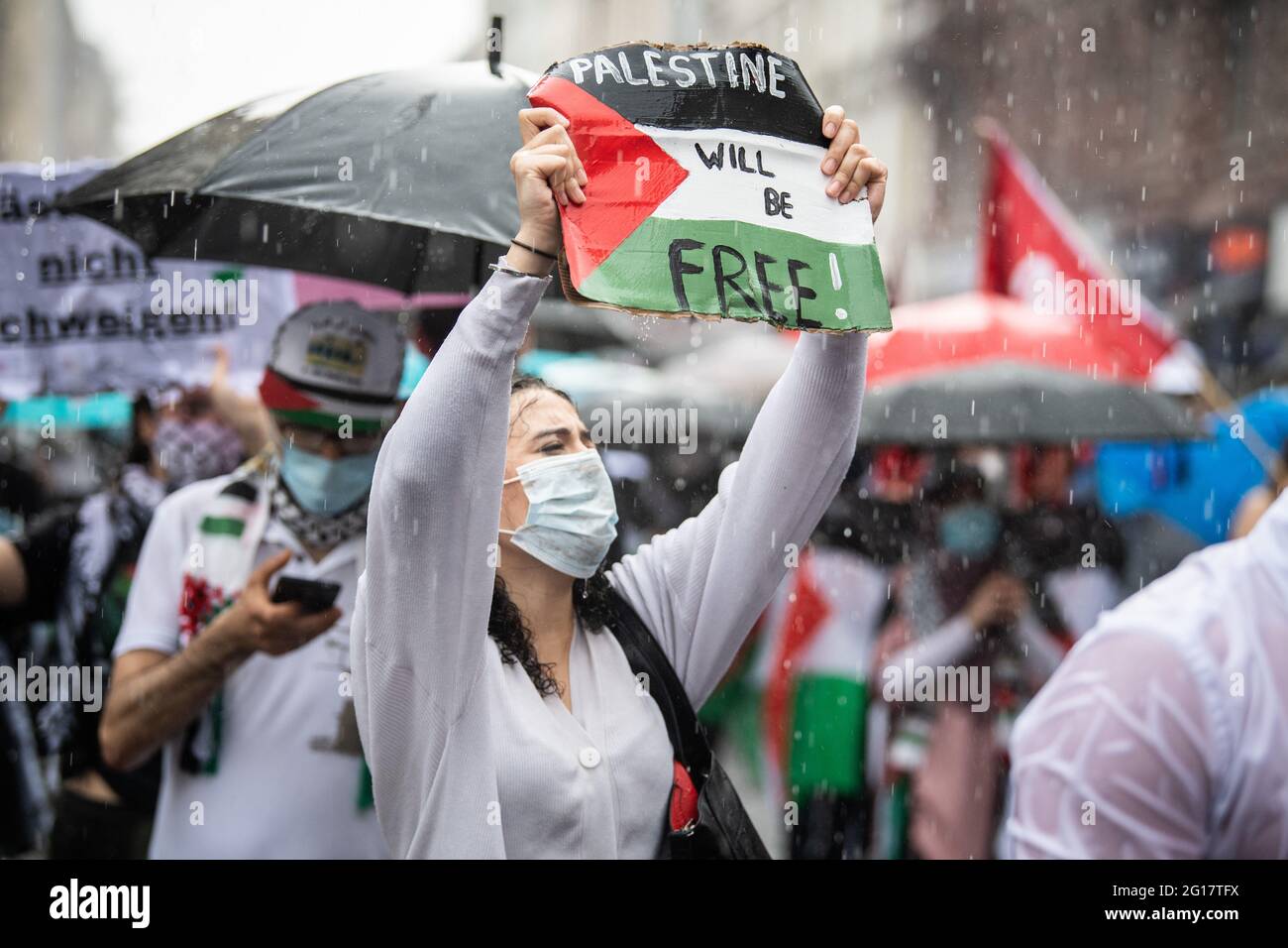 05 giugno 2021, Hessen, Francoforte sul meno: Un partecipante a una manifestazione ha in mano un cartoncino con la bandiera palestinese sul quale è scritto: "La Palestina sarà libera! In una pioggia simile al cloudburst, i partecipanti a una manifestazione pro-Palestina con il motto 'Naksa Day, Long Live the Resistance' si sono recati a Francoforte. La polizia ha garantito la marcia di protesta con un grande contingente. Foto: Boris Roessler/dpa Foto Stock
