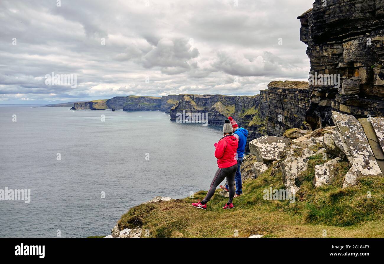 I viaggiatori ad esplorare le scogliere di Moher su nuvoloso giorno, County Clare, Irlanda, Europa 2018 Foto Stock