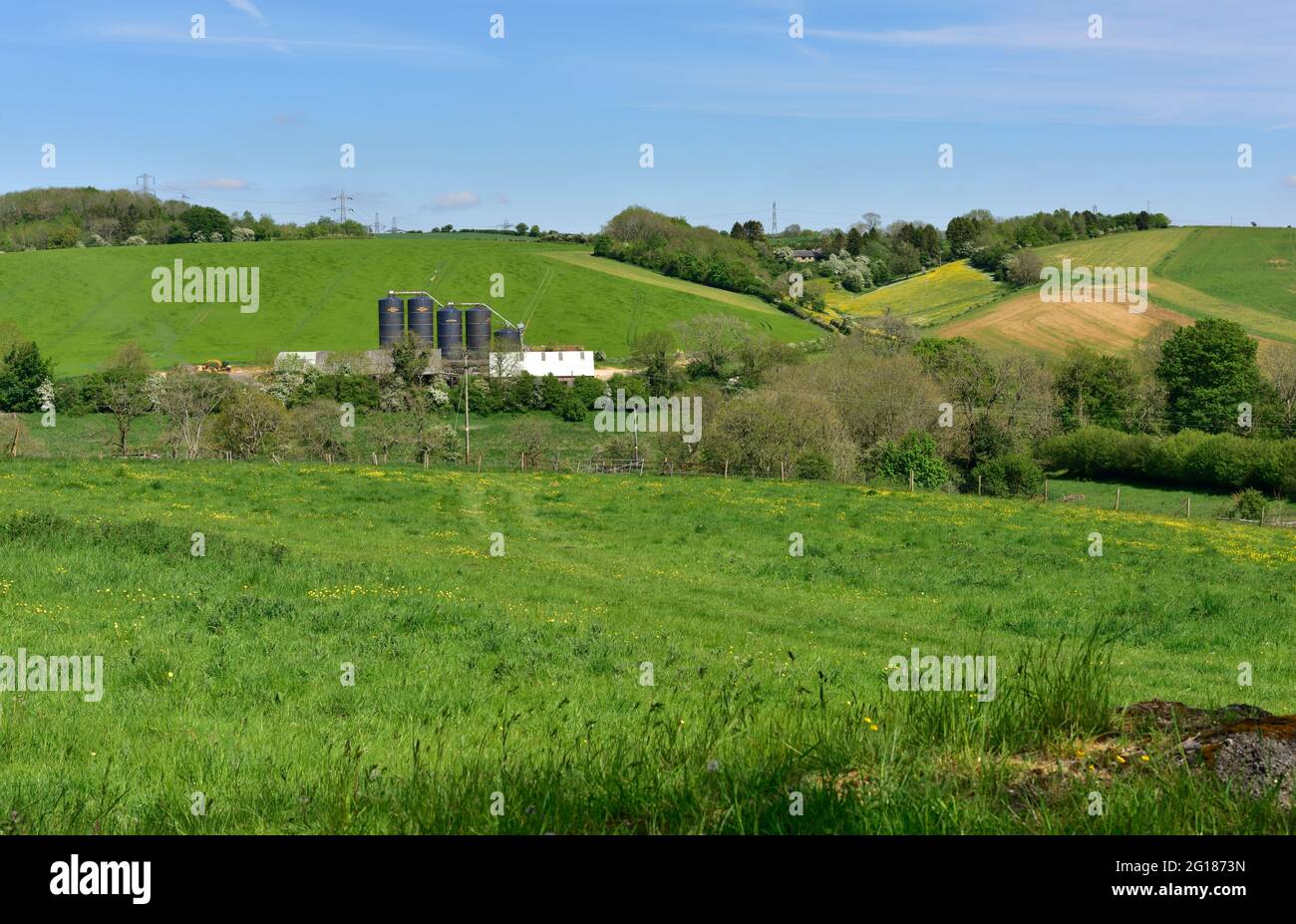 Campagna con terreni agricoli e silos di stoccaggio nel distretto di Cotswold di Gloucestershire, Regno Unito Foto Stock