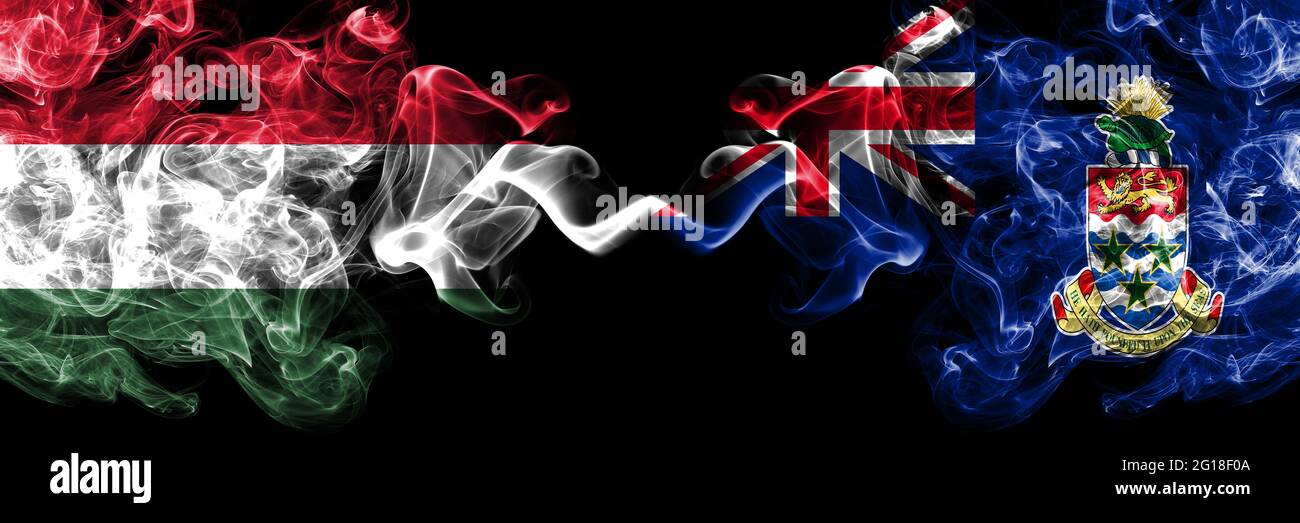 Ungheria, Ungheria vs. Regno Unito, Gran Bretagna, Isole Cayman bandiere fumose fianco a fianco. Foto Stock