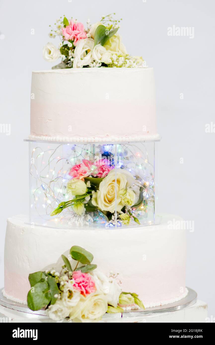 Torta a più livelli per matrimoni o compleanni. Bella torta festosa bianca e rosa decorata con fiori. Foto Stock