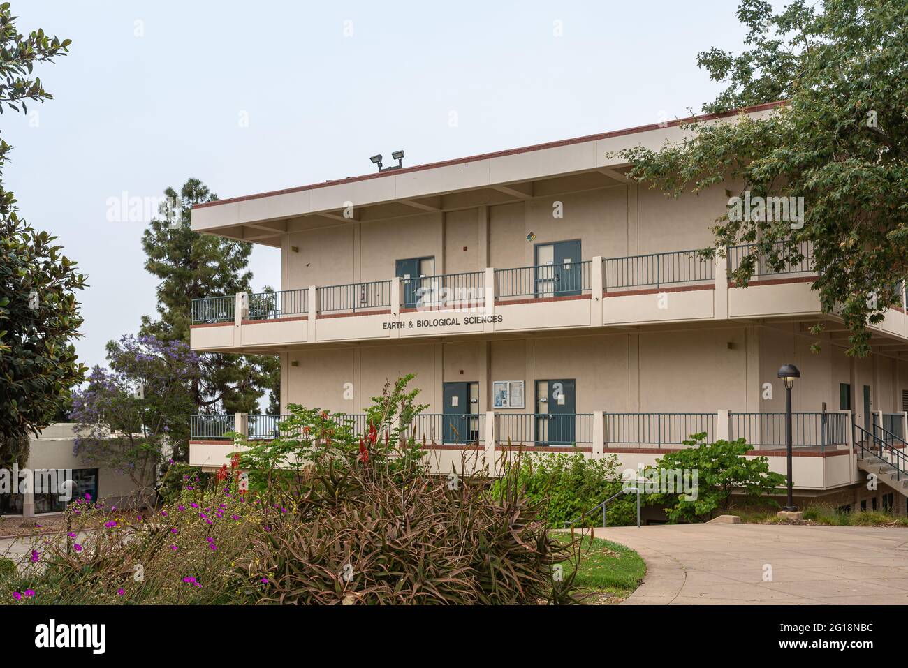 Santa Barbara, CA, USA - 2 giugno 2021: Strutture del City College. Beige Eartt e Biological Sciences edificio situato in un paesaggio verde sotto il cielo grigio. Flowe Foto Stock