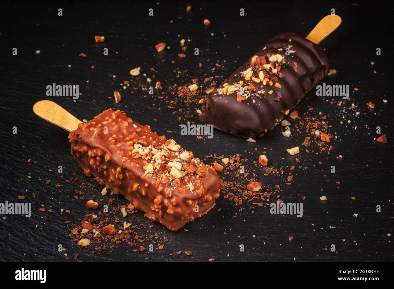 Torta al cioccolato schiocchi con noci in forma di pop-sicle su bastone su sfondo di ardesia nera Foto Stock