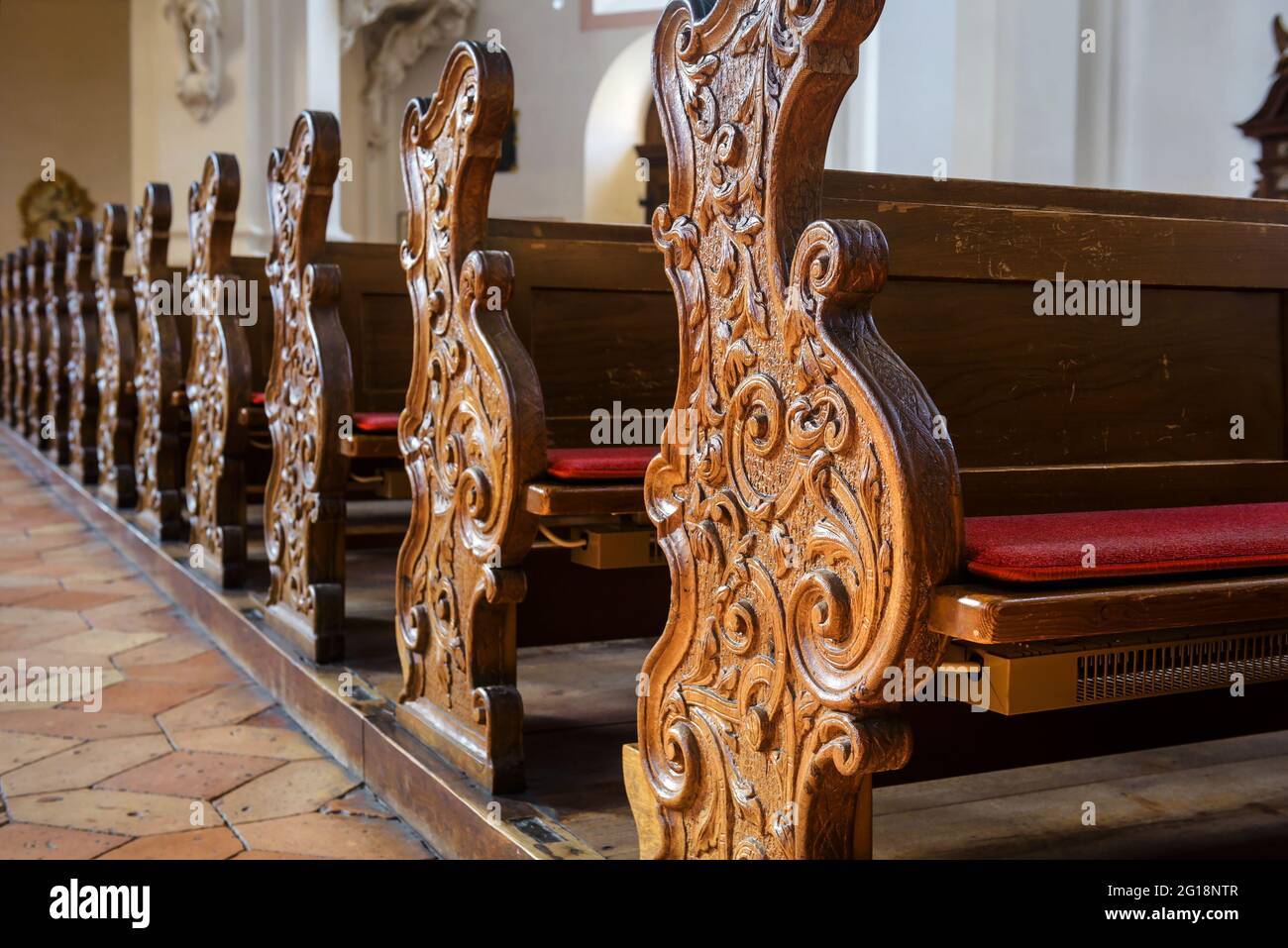 Banchi vuoti all'interno della chiesa in primo piano, banchi in legno intagliato nella cattedrale cattolica, dettaglio dell'interno della chiesa cristiana. Belle vecchie panche, panchine di culto Foto Stock