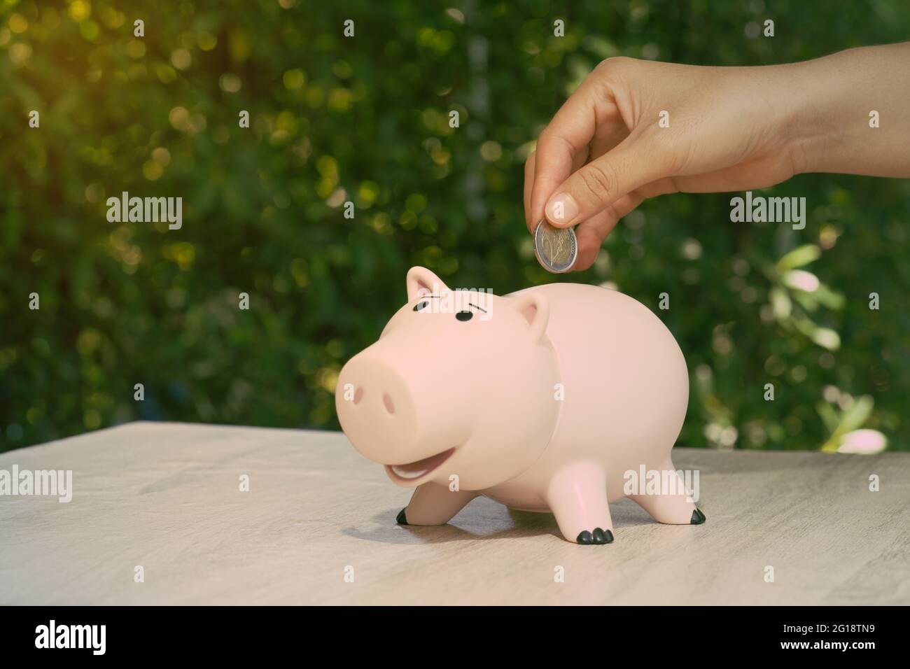Mano astratta mettere la moneta in porcellino banca su scrivania idee per guadagnare un reddito di affari e risparmio per la pianificazione di pensione. Foto Stock
