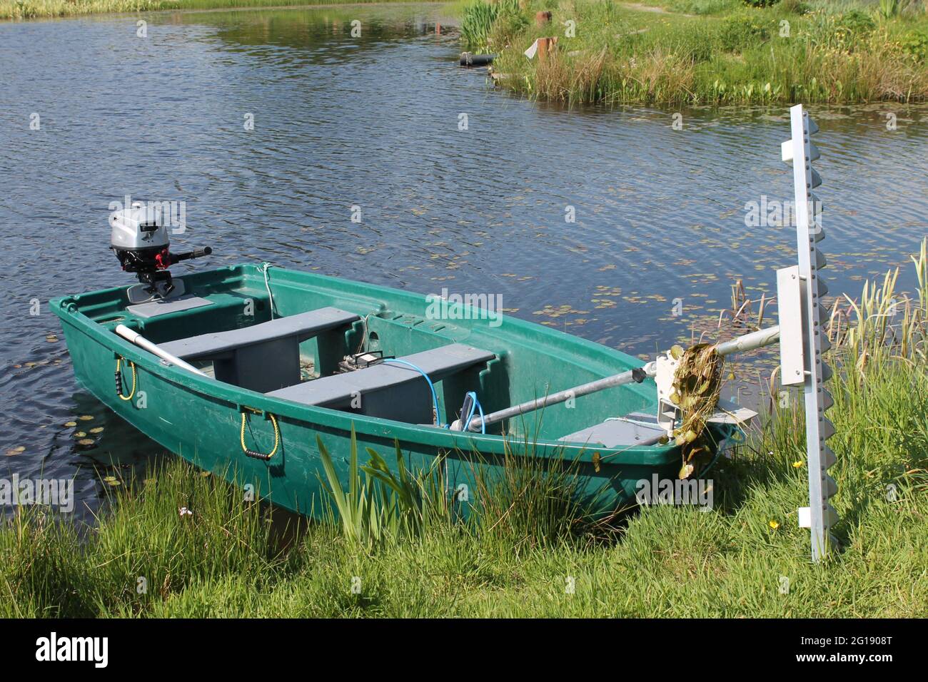 Pesca barca a motore con taglierina erbaccia attaccato sul bordo di un lago di pesca con spazio di copia Foto Stock