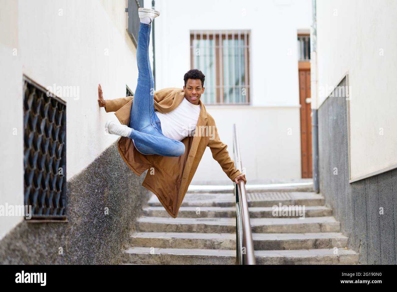 Giovane uomo nero che salta per gioia su un corrimano in strada. Foto Stock