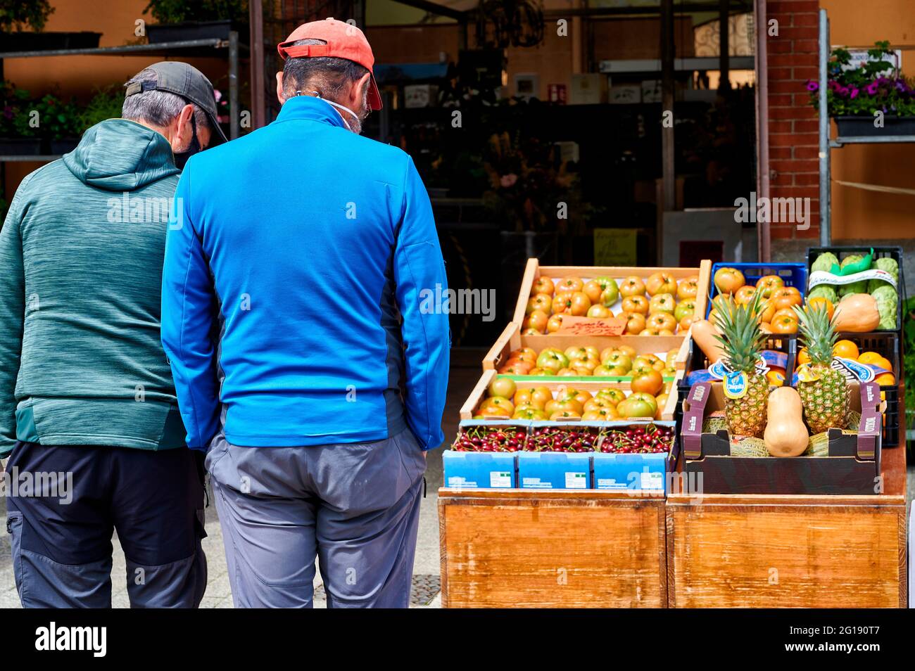 La gente che indossa la maschera di faccia che guarda la frutta al drogheria Foto Stock