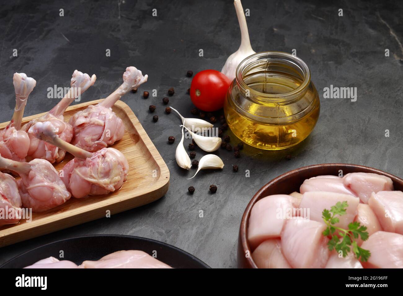 I tagli grezzi del pollo combo, combinazione dei tagli biriyani del pollo, dei tagli della frittura del pollo e del lollipop del pollo disposti su una tavola di legno con la foglia del coriandolo, gar Foto Stock