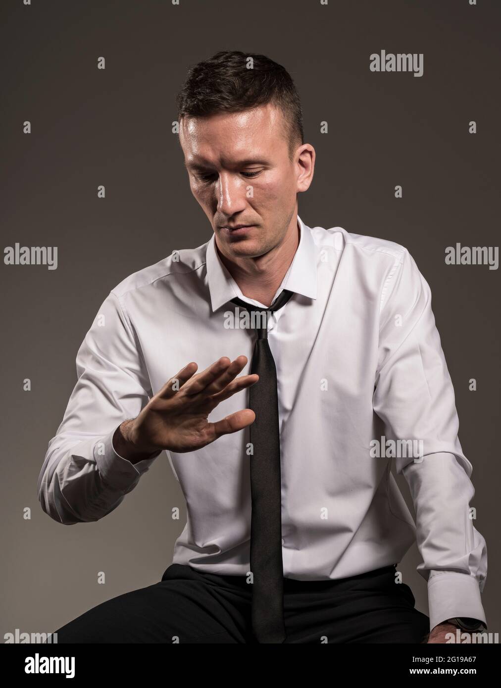 Uomo in camicia bianca e cravatta guarda la mano. Foto Stock