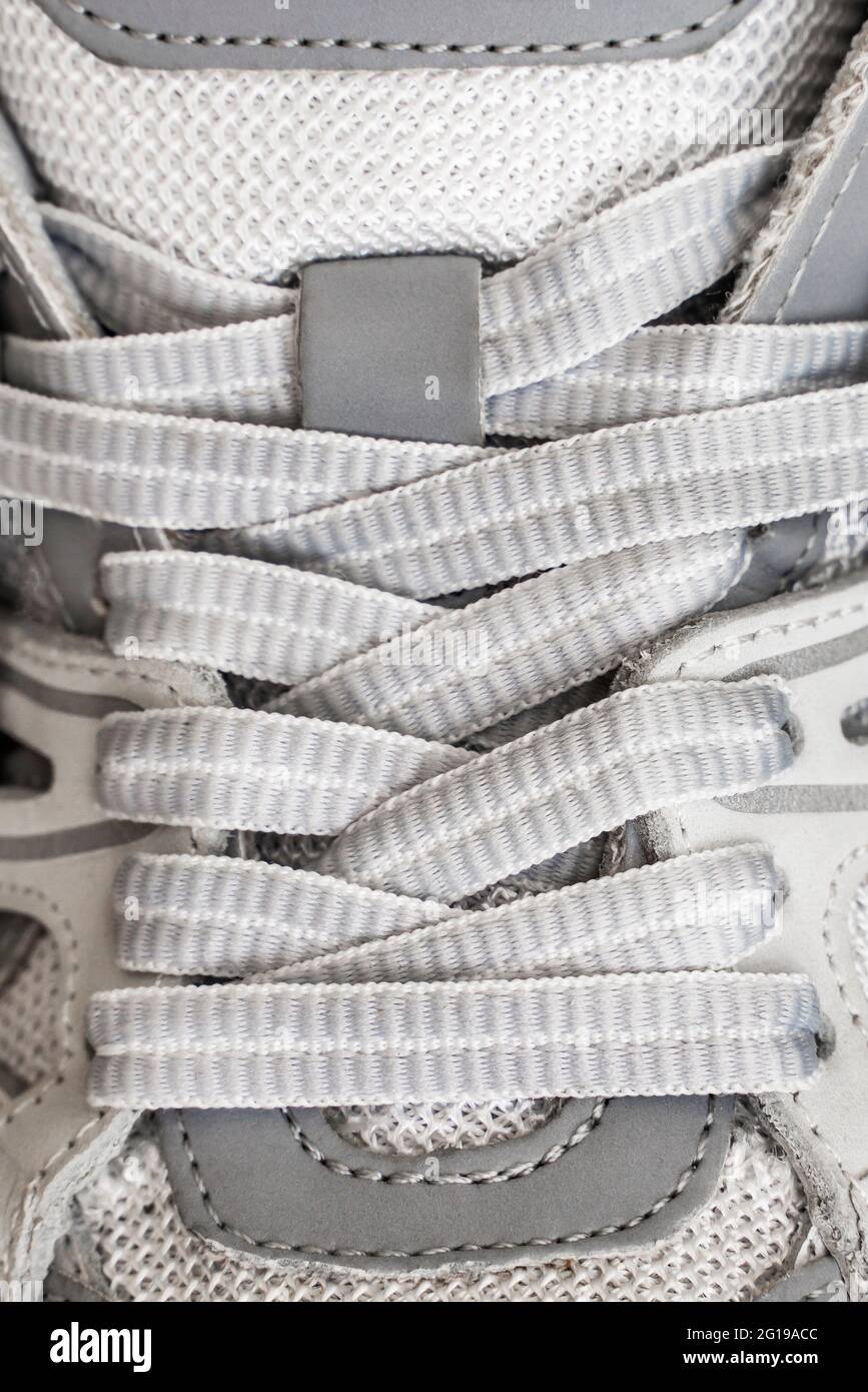 Lacci grigi, sfondo grigio sportivo. Primo piano delle sneakers sportive con allacciatura. Foto Stock
