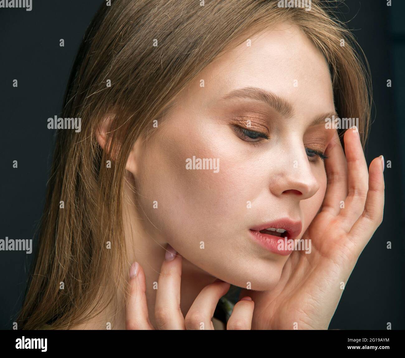 Primo piano di donna con mal di testa sfregando i suoi templi a casa. Giovane donna con mal di testa su sfondo scuro. Foto Stock