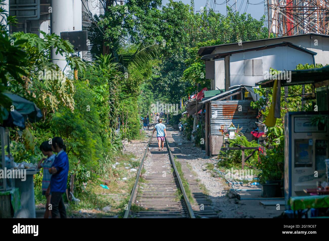 Le bancarelle del mercato e le case del ramphackle si trovano accanto a una linea ferroviaria a Bangkok in Thailandia nel Sud Est asiatico. Foto Stock