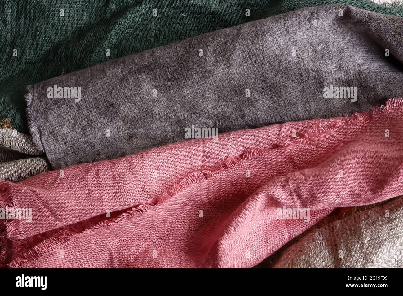 Tessuto di lino di diversi colori. Sfondo tessile. La biancheria è rosa, grigia e verde. Foto Stock