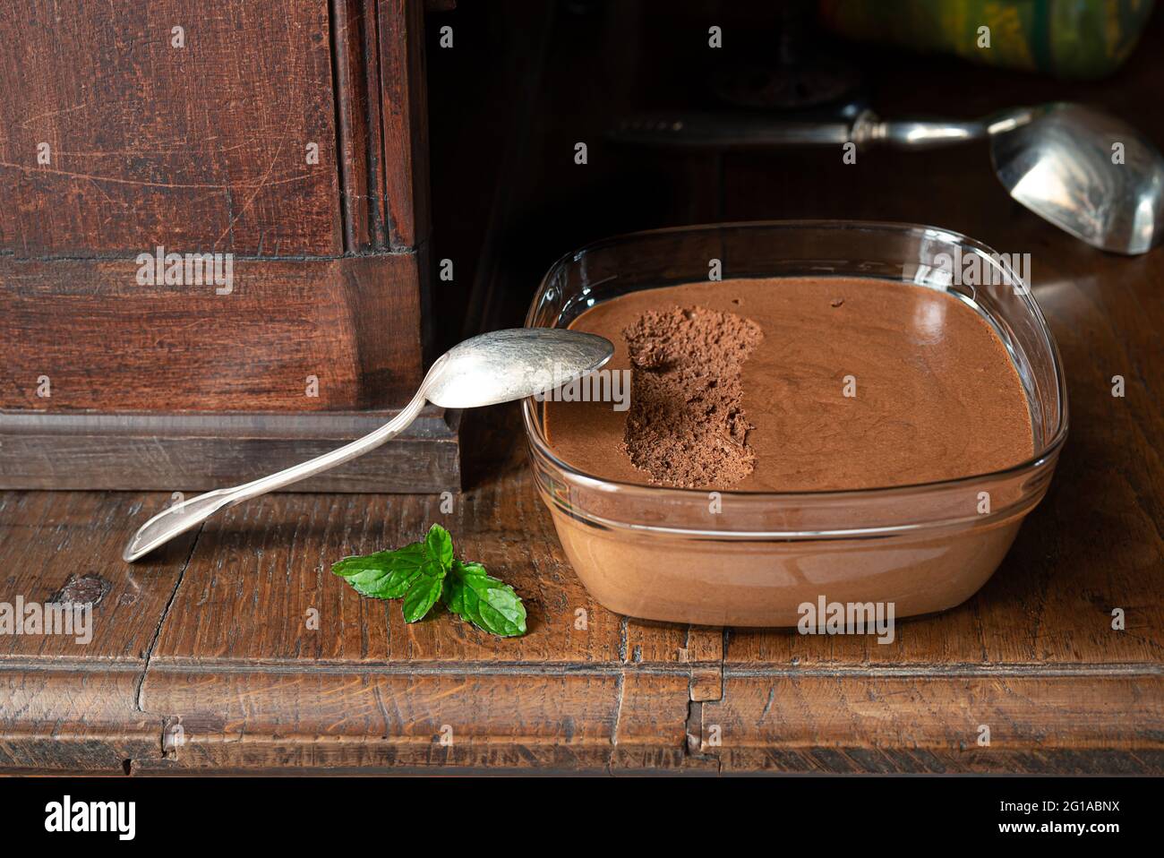 Ciotola trasparente con mousse al cioccolato francese tradizionale su una vecchia sponda in legno Foto Stock