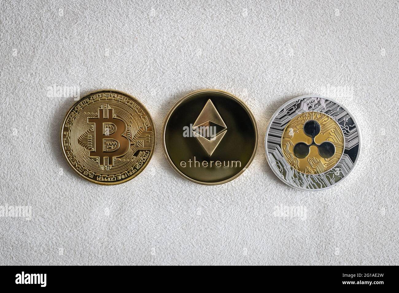 Bitcoin, Ethereum e ripple criptovalute, monete fisiche su sfondo bianco. Foto Stock