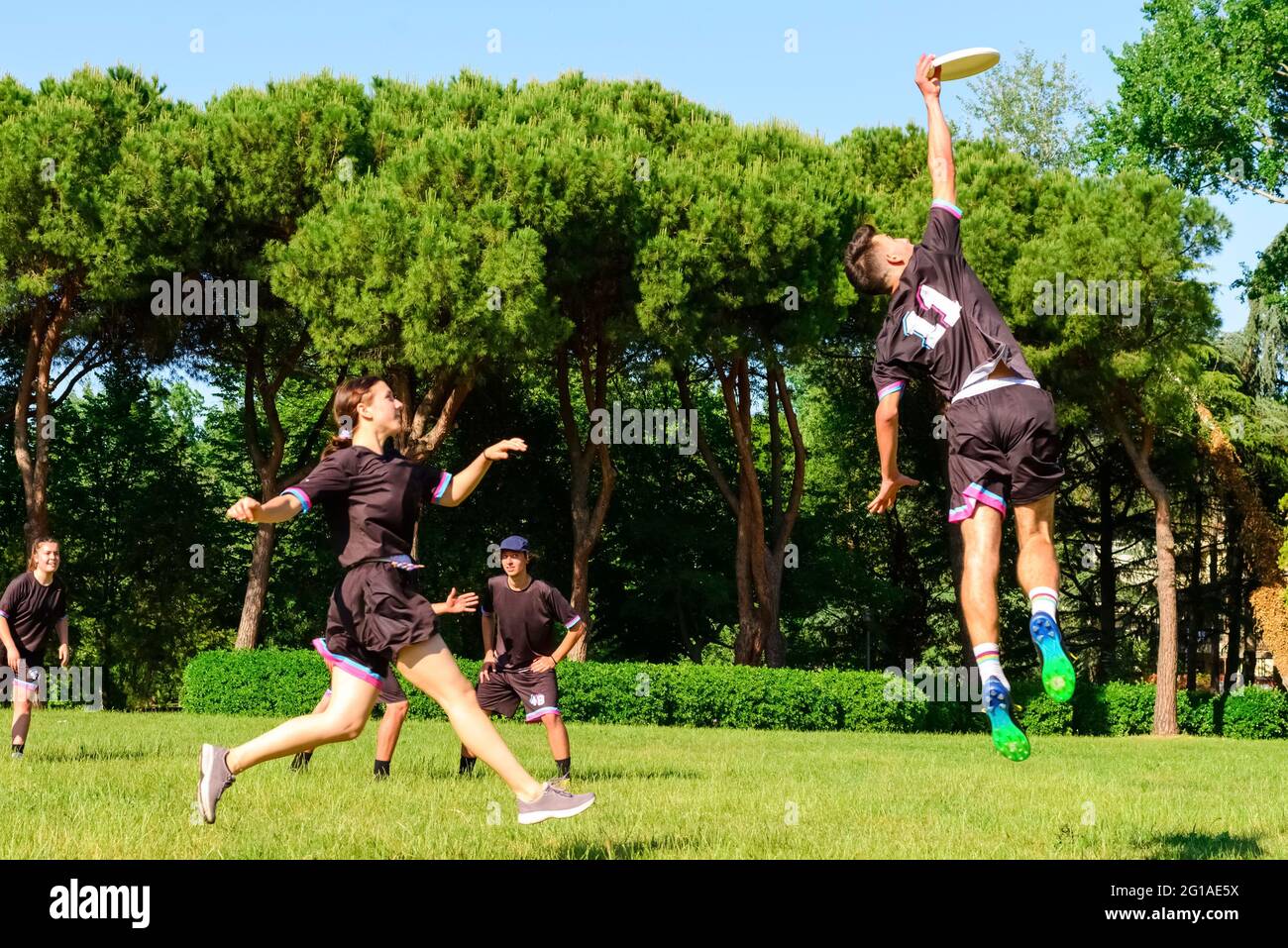 Gruppo di giovani adolescenti in squadra indossare giocare una partita di frisbee nel parco oudoors. Salto uomo prendere un frisbee a un compagno di squadra in un frisbee finale Foto Stock