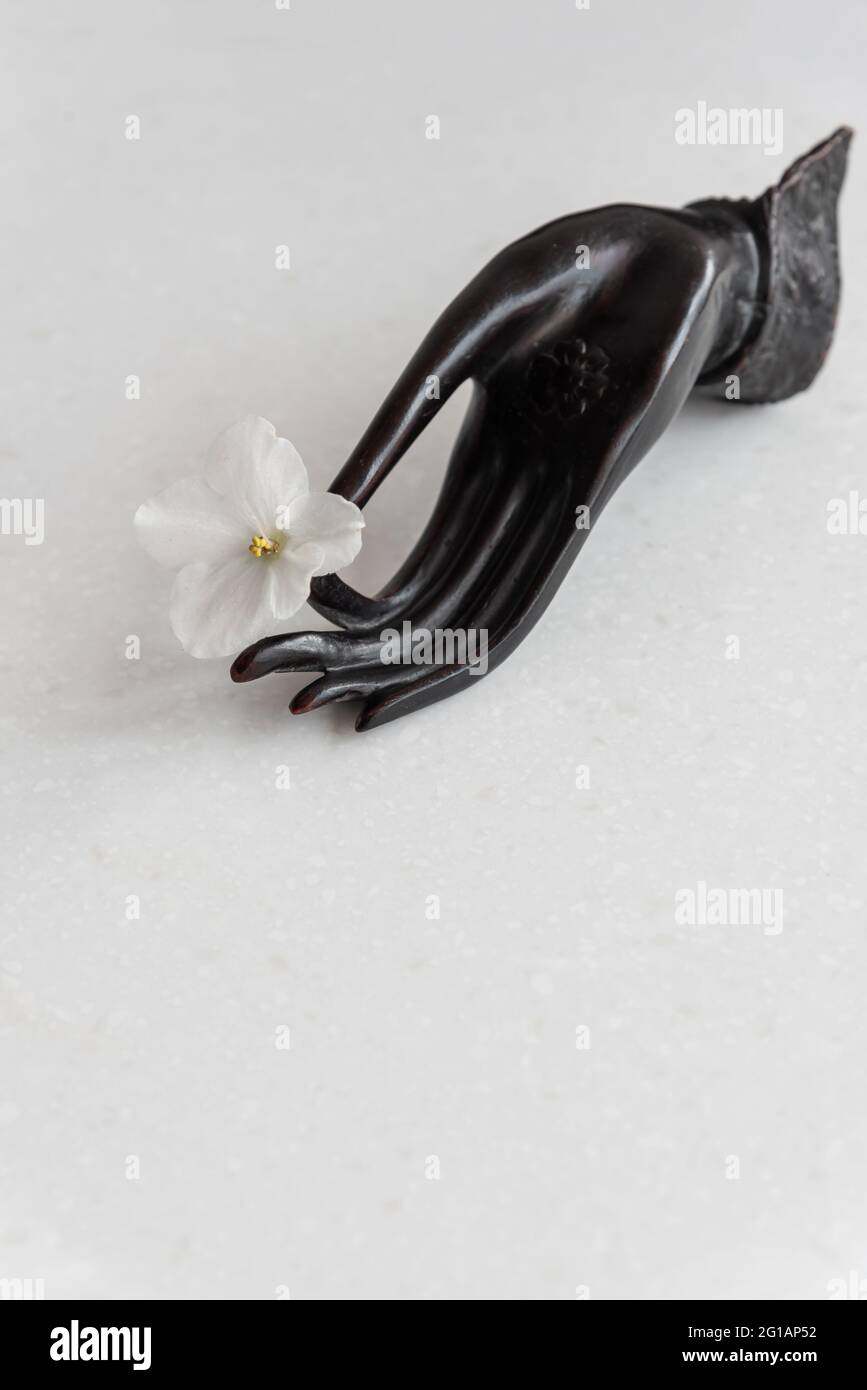 Mano decorativa in mudra con fiore fresco sul tavolo Foto Stock